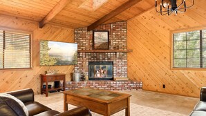 A cozy living room with a brick fireplace, leather sofas, and a large window.