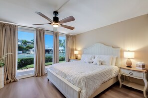 A hotel room with a large bed, a ceiling fan, a nightstand with a lamp, and a view of the outdoors. - Beach lovers dream (Longboat Key)