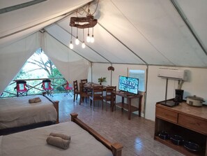 A tent with two beds, a dining area, a TV, and a kitchenette. - Volcano Tenorio Glamping Ranch - 3 Tents (San Rafael de Guatuso)