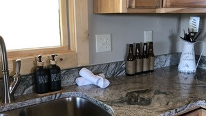 A kitchen with granite countertops, wooden cabinets, a stainless steel sink, and a window. - Hot tub-petfriendly-firepit-pool table-bar-3+acres (McHenry)