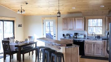 A spacious kitchen with wooden cabinets, a central island with stools, a ceiling fan, and a dining area with a table and chairs.