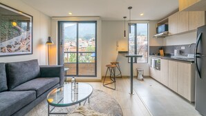 Un apartamento moderno con sala de estar, cocina y ventanas amplias que ofrecen vistas de la ciudad.