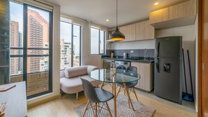 Una cocina moderna con una mesa de comedor de vidrio, un sofá y un ventanal con vistas a la ciudad.