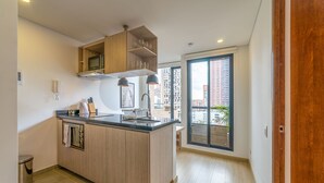 Una cocina moderna con una isla central, armarios de madera y vistas a un paisaje urbano a través de un ventanal amplio.