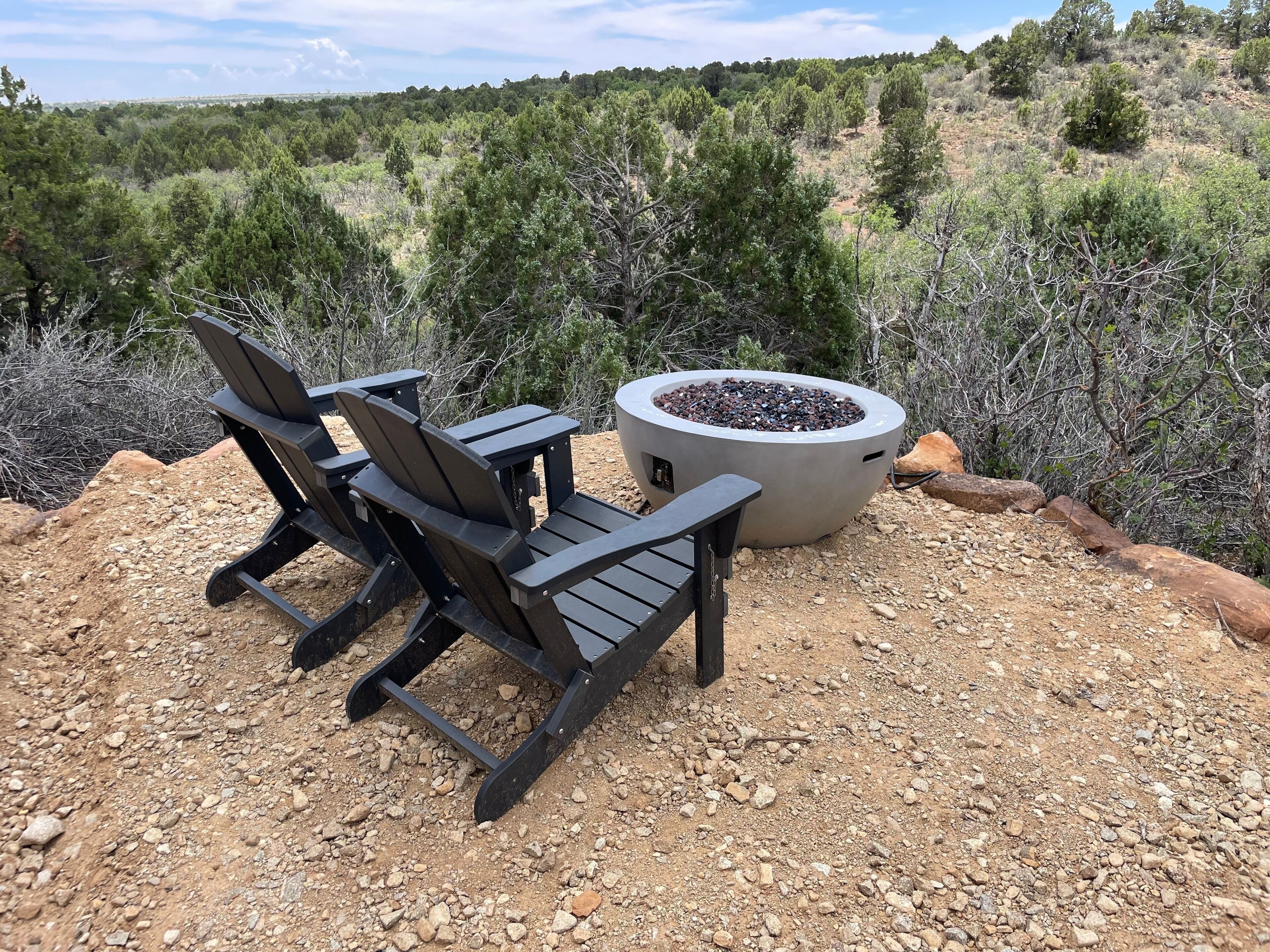 An outdoor seating area with two Adirondack chairs and a fire pit.