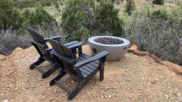 An outdoor seating area with two Adirondack chairs and a fire pit.
