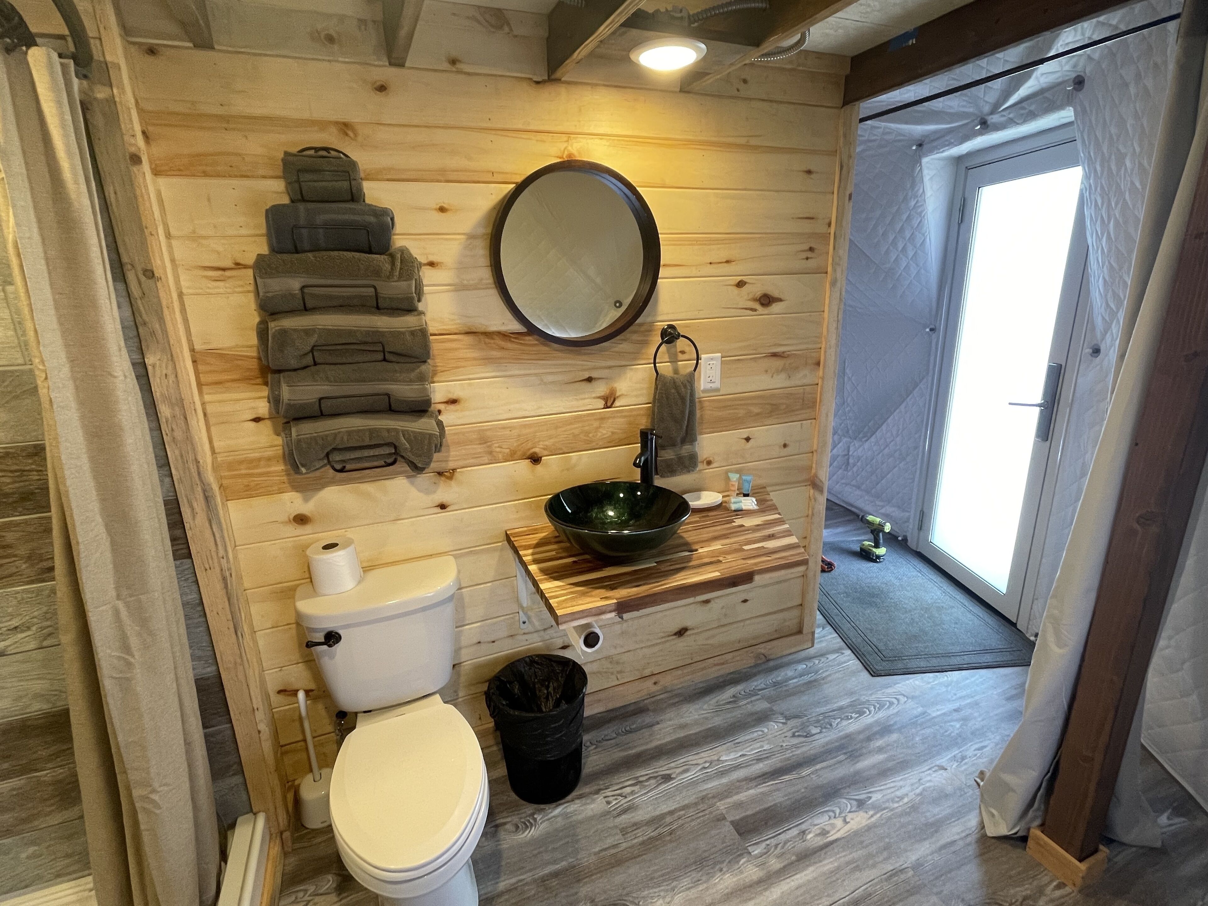 Ein Badezimmer aus Holz mit Toilette, Waschbecken und Spiegel.