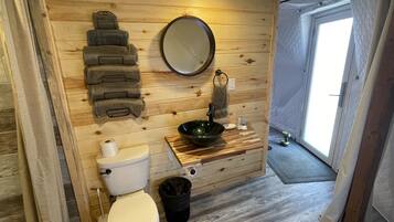 Ein Badezimmer aus Holz mit Toilette, Waschbecken und Spiegel.