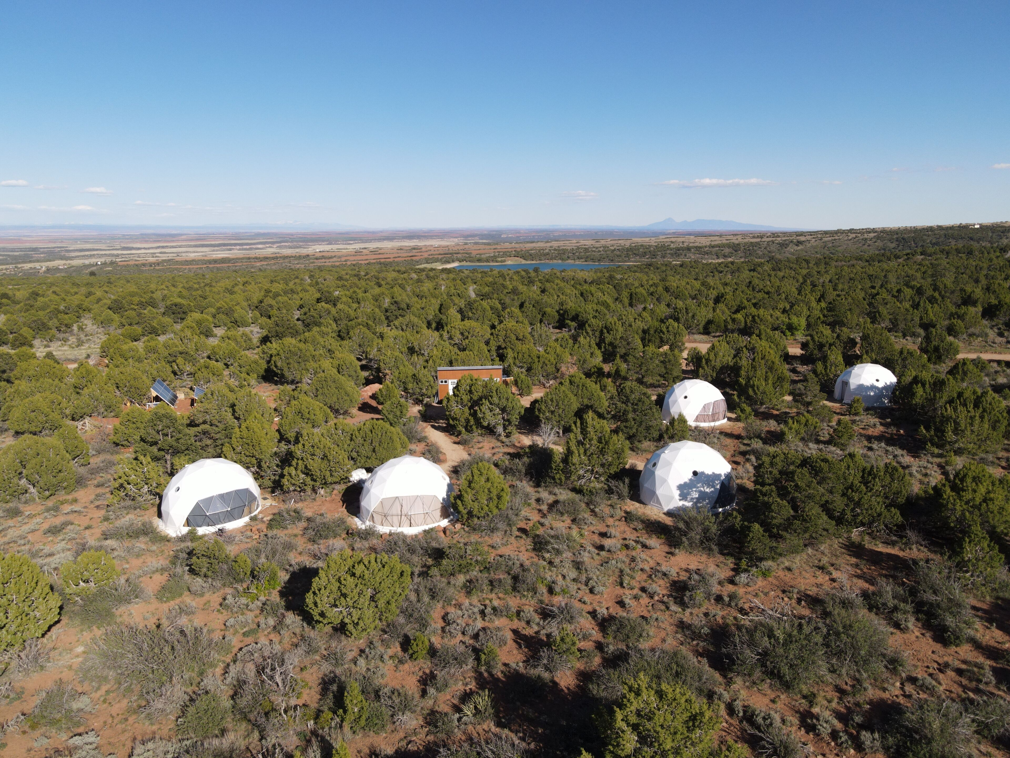 A remote area with several dome-shaped structures surrounded by dense vegetation and a few buildings.
