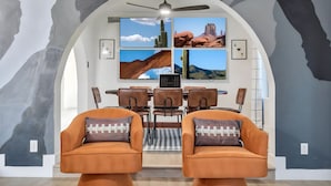A dining area with a modern design, featuring a ceiling fan, a dining table with chairs, and a wall with framed photographs. - Scottsdale Paradise! Basketball, Heated Pool, Golf (Scottsdale)