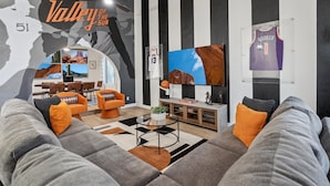 A living room with a large mural, a TV, and a basketball jersey on the wall. - Scottsdale Paradise! Basketball, Heated Pool, Golf (Scottsdale)