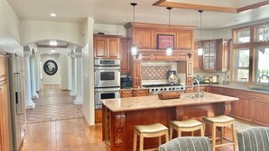 Una cocina amplia con armarios de madera, electrodomésticos de acero inoxidable y una isla grande con taburetes de bar.