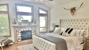 Un dormitorio con una cama grande, una chimenea de piedra y una decoración con cabeza de toro.