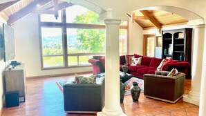 Un salón amplio con un ventanal grande, un sofá rojo y una chimenea.