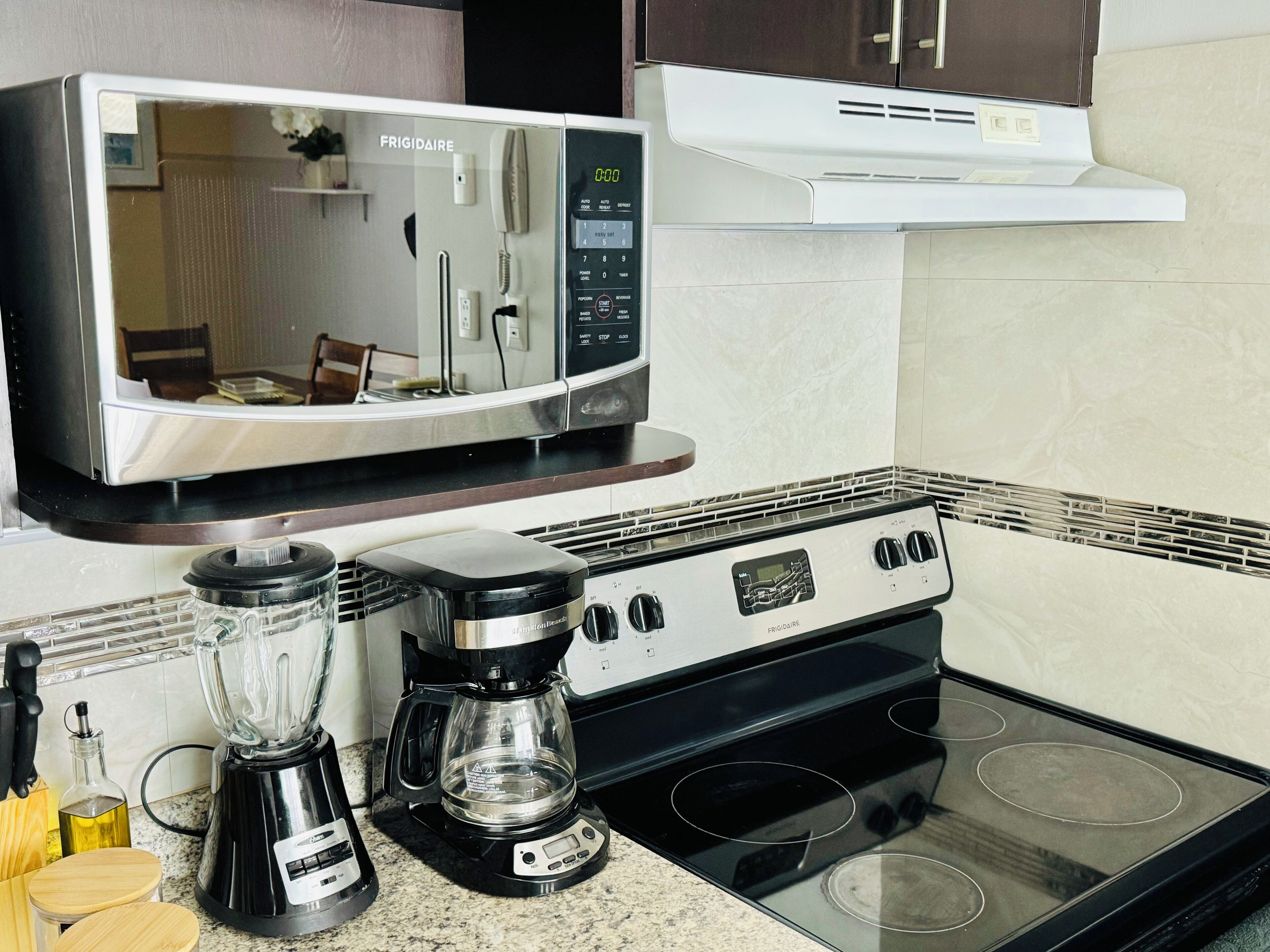 A kitchen with a microwave, coffee maker, and stove.