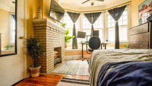 Une chambre avec une cheminée en briques, un tapis de course et un grand lit.