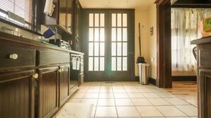 Une cuisine avec des meubles de rangement en bois, un sol carrelé et une porte donnant sur une autre pièce.