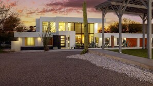 Una casa moderna con un porche cubierto y un cactus grande en el jardín delantero.