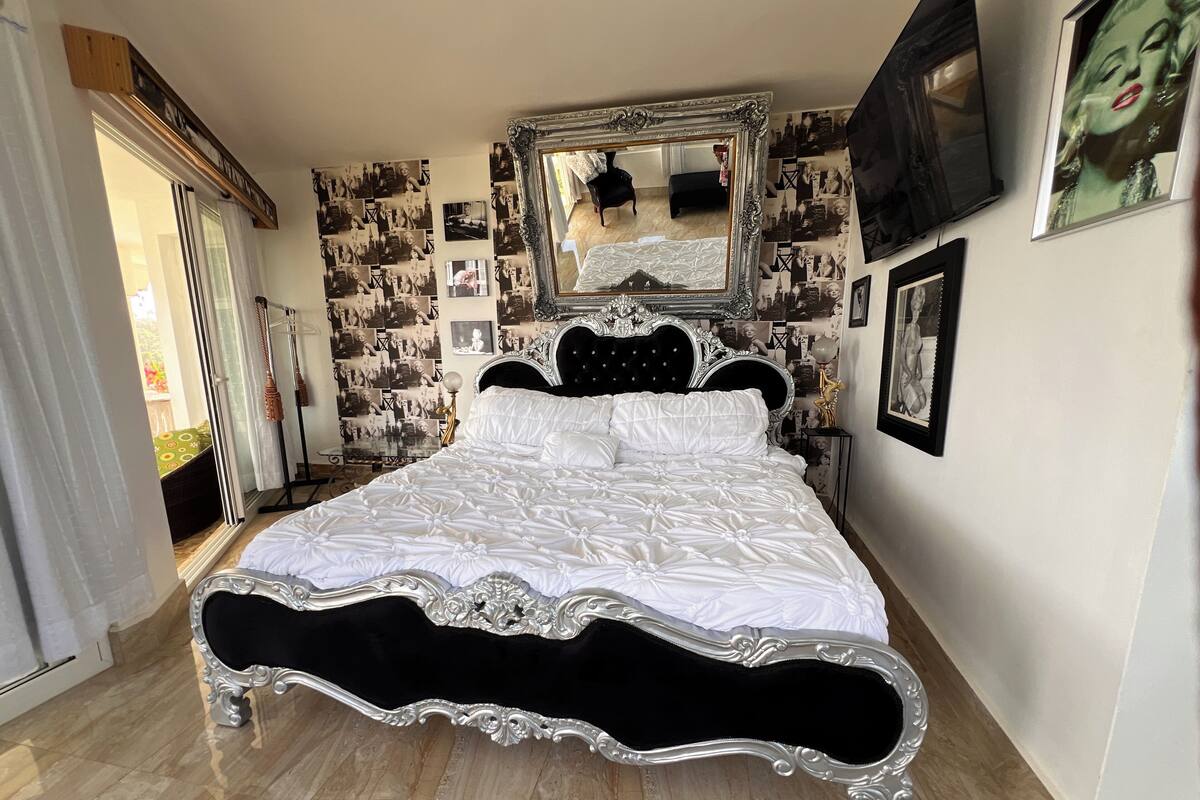 Un dormitorio con una cama grande, cabecera ornamentada y un espejo encima.