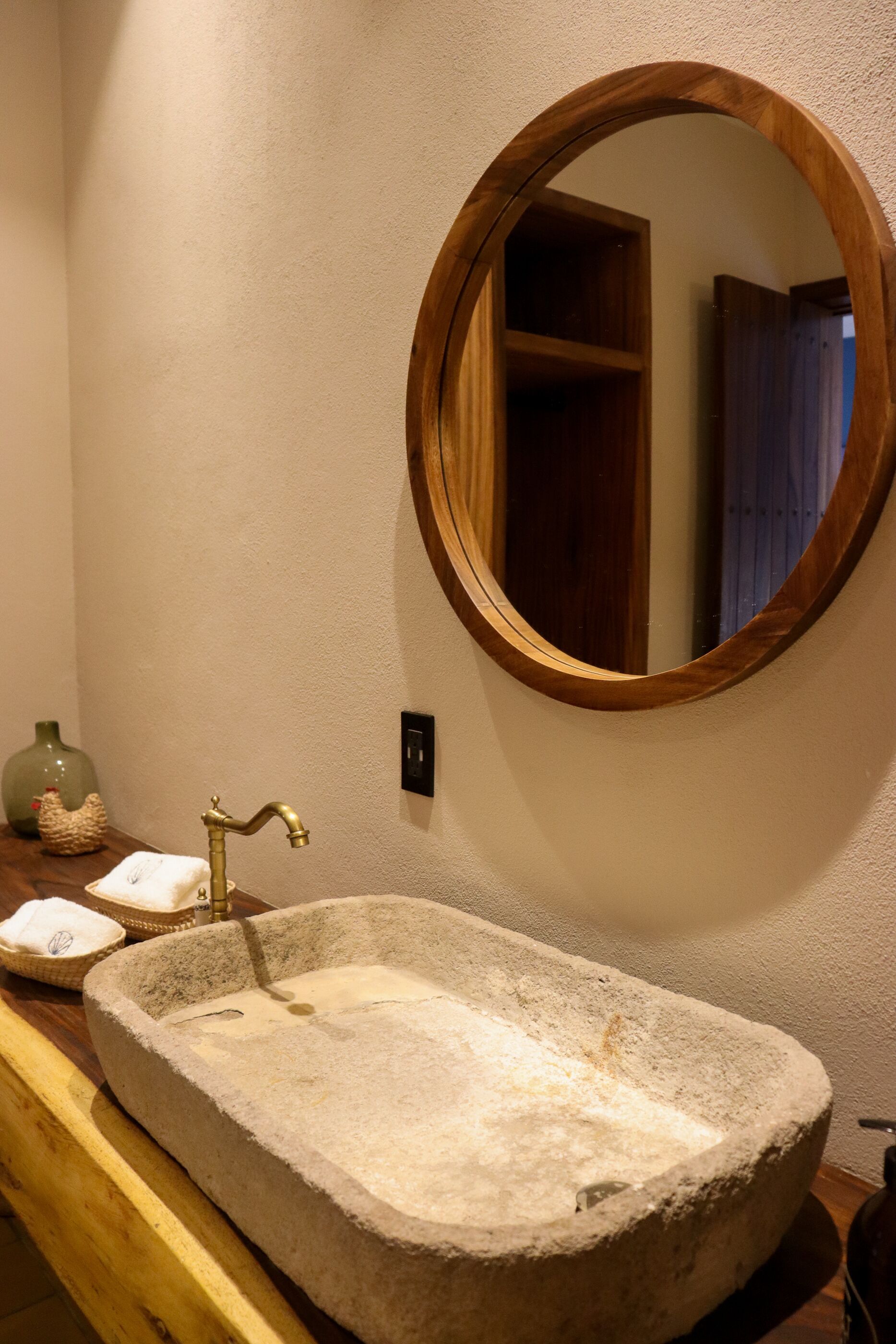 A bathroom with a stone sink, a wooden-framed mirror, and a wooden cabinet.