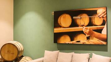 A living room with a green wall, a beige sofa, and wooden barrels in the background.