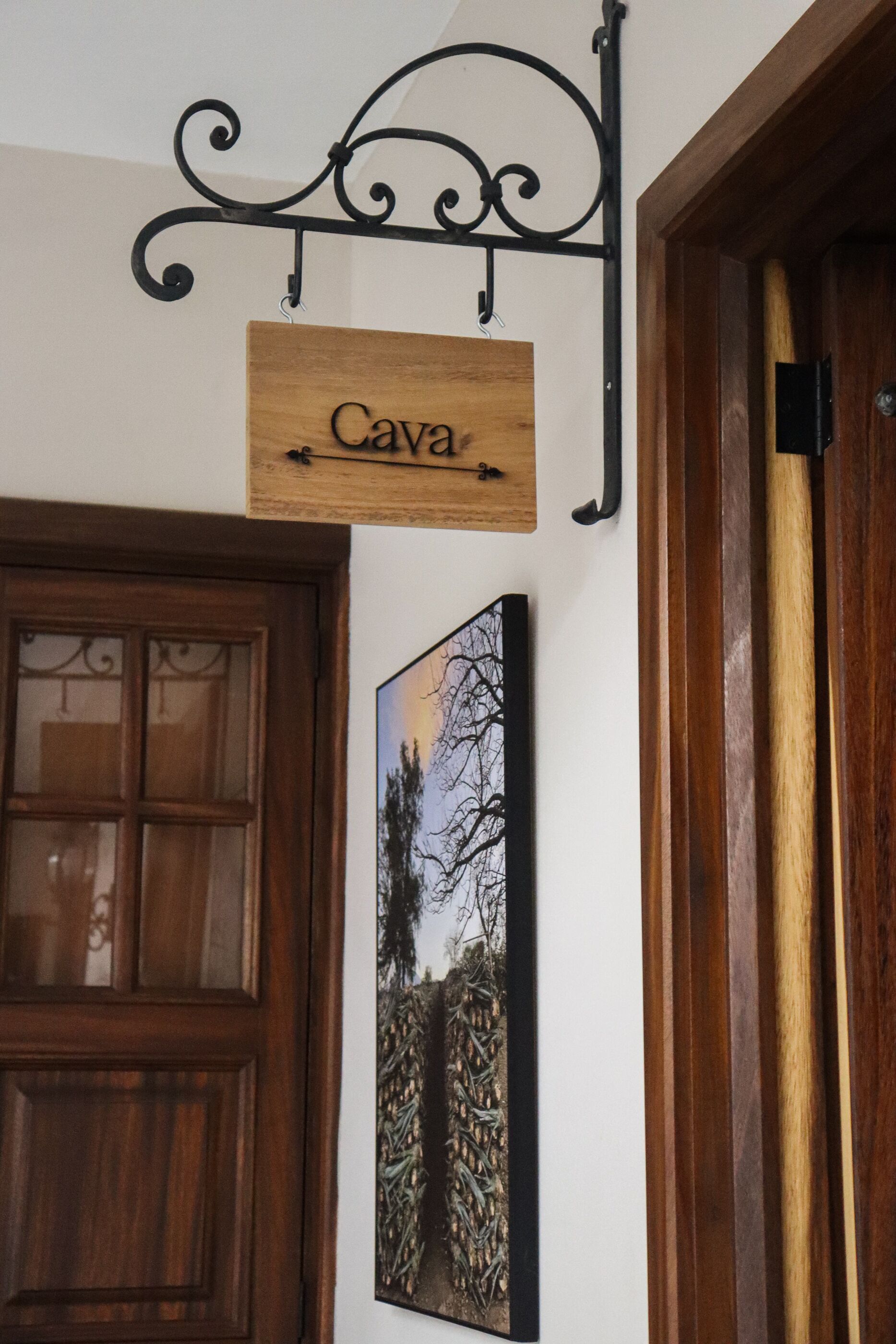 A wooden sign with the name 'Cava' hanging from a metal fixture above a door.