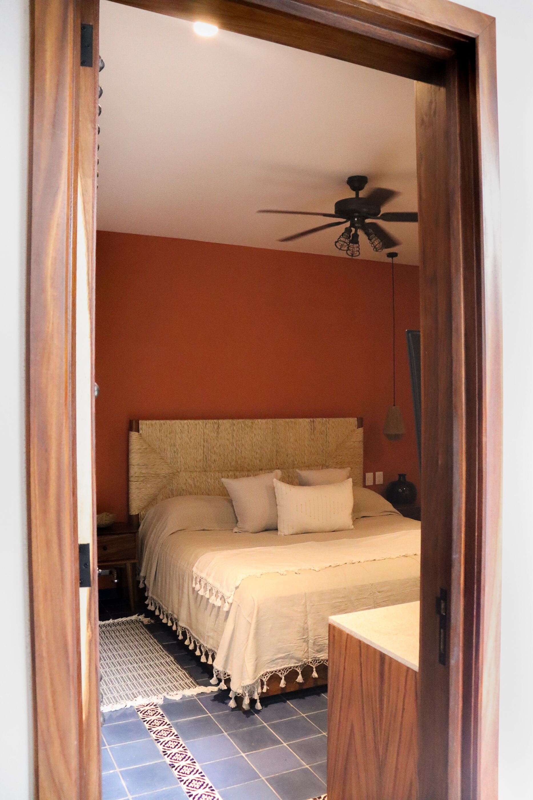 A bedroom with a bed, a ceiling fan, and a nightstand.