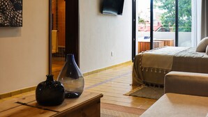 Una habitación de hotel con una cama, un cofre de madera, un jarrón, un televisor y un ventanal con vistas al exterior.
