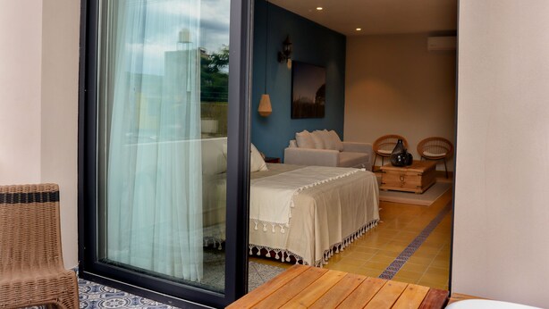 Un dormitorio con cama, sofá, dos sillones, una mesa de madera y un ventilador de techo.