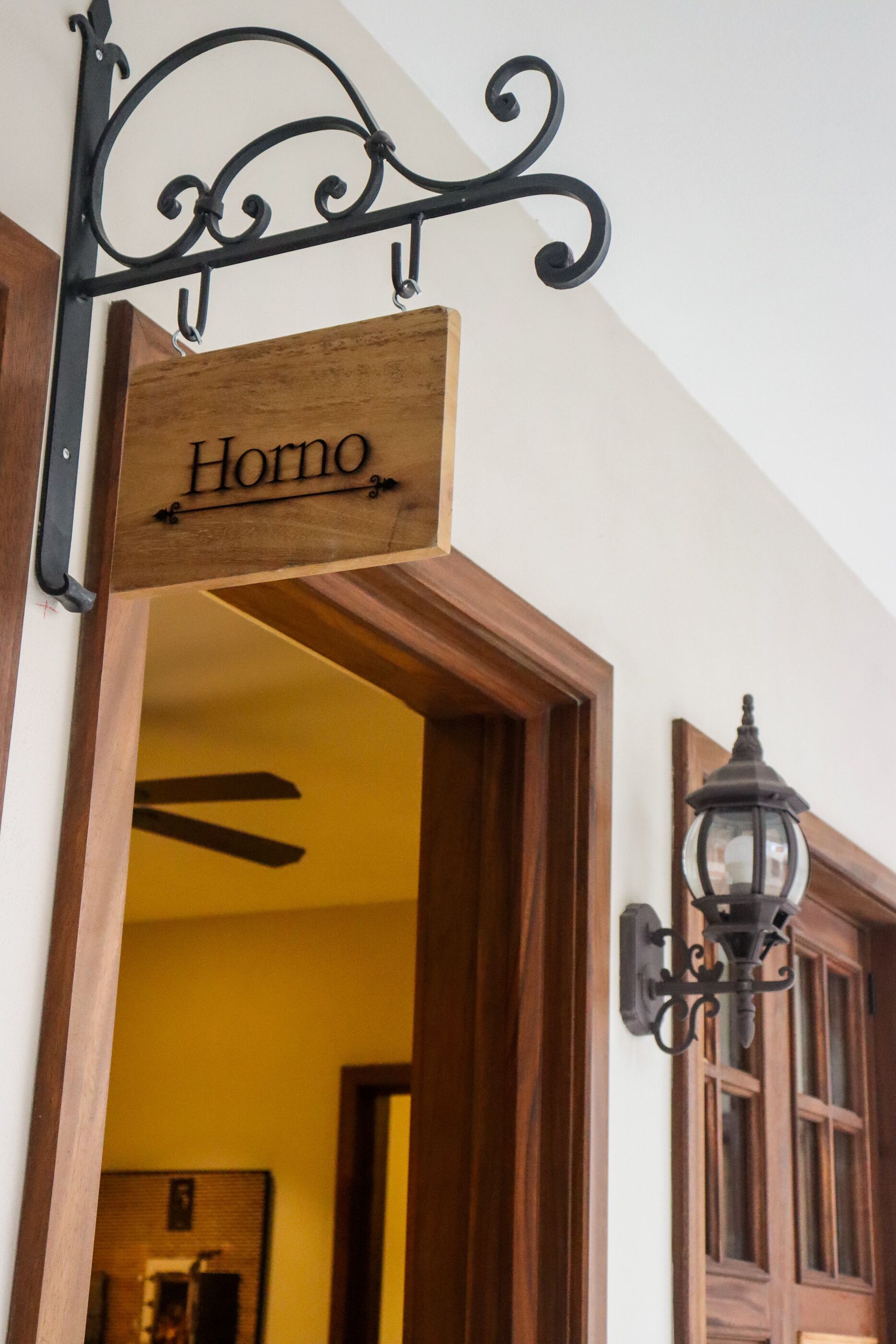 A wooden sign with the name "Horno" hanging above a doorway.