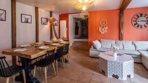Zona pranzo con tavolo in legno apparecchiato per sei persone, sedie nere e lampadario.
