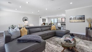 A modern living room with a sectional sofa, a glass coffee table, and a fireplace. - The Sophey (Denison)