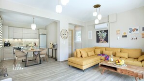 Una sala de estar moderna con un sofá amarillo, una mesa de centro de madera y una zona de comedor con una mesa y sillas.