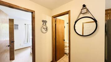Un couloir avec une porte en bois, un miroir et une pancarte de bienvenue.