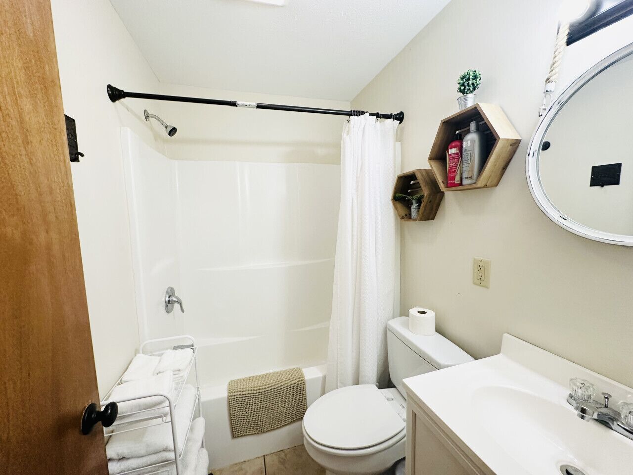 A bathroom with a shower, toilet, sink, and a towel rack.