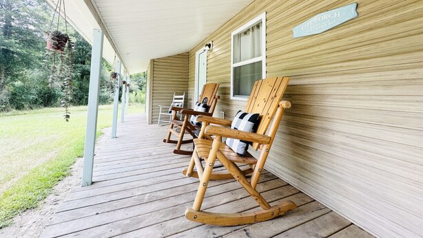 A wooden porch with rocking chairs and a hanging plant.