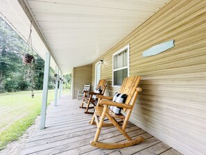 A wooden porch with rocking chairs and a hanging plant.