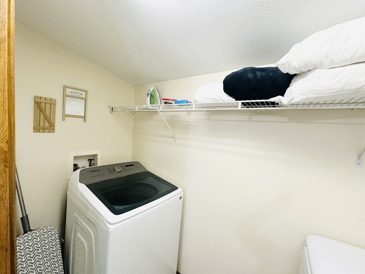Ein Waschbereich mit Waschmaschine, einer Ablage für Kissen und einem Wäschehinweisschild an der Wand.