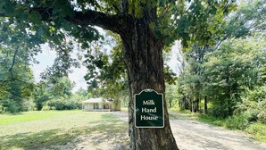 A tree with a sign reading "Milk Hand House" in a rural setting.