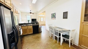 Una cocina con refrigerador, estufa y mesa de comedor con sillas.