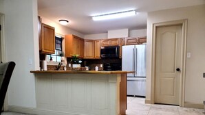 Una cocina con armarios de madera, una isla central, un refrigerador y un microondas.