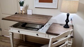 Una mesa de comedor con un banco, una lámpara, un cartel enmarcado y una planta en maceta.