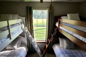 A room with bunk beds, a window with curtains, and a hanging light fixture.
