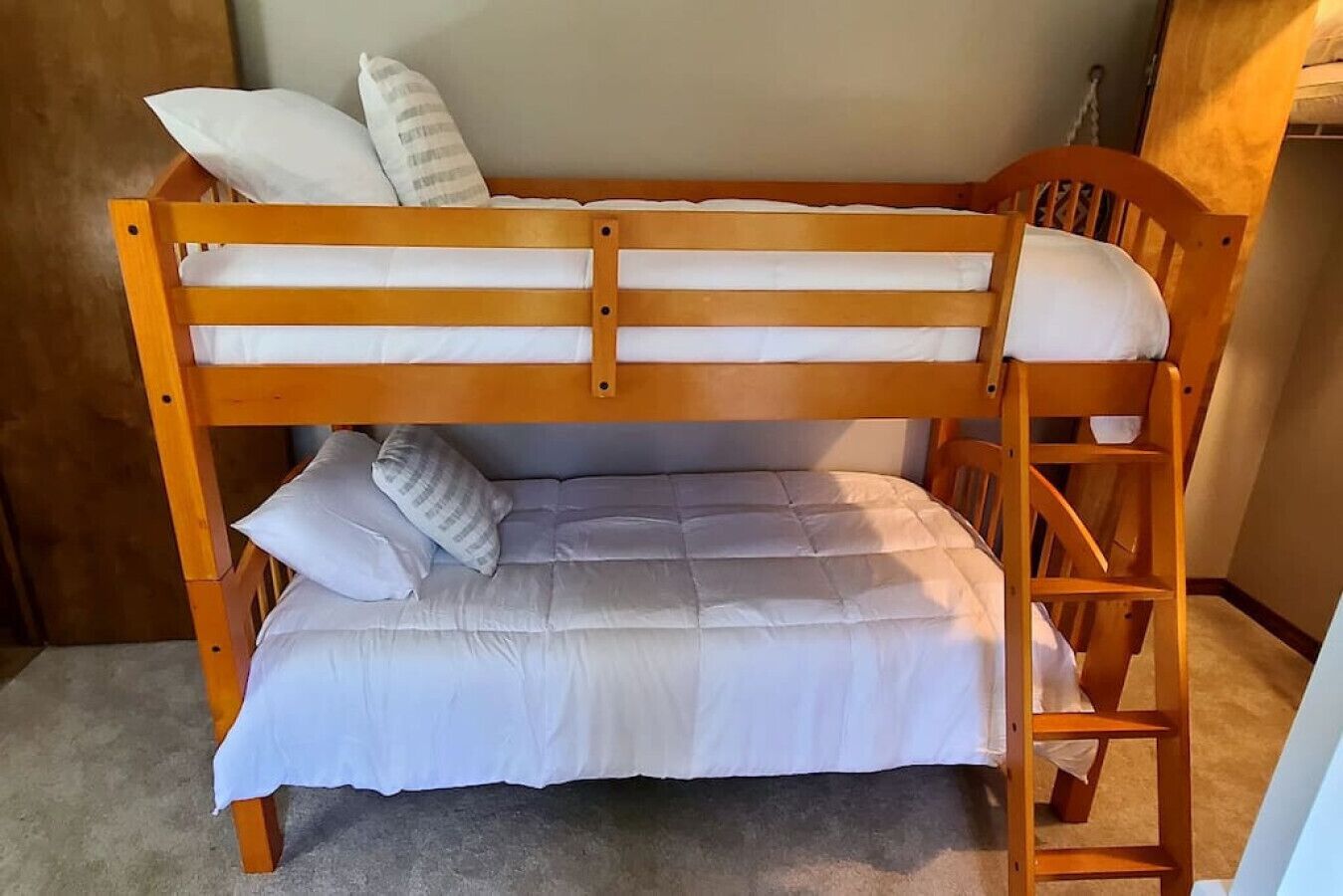 Una cama litera de madera con ropa blanca y almohadas.