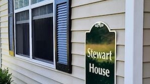 Une maison avec une fenêtre et une enseigne sur laquelle on peut lire « Stewart House ».