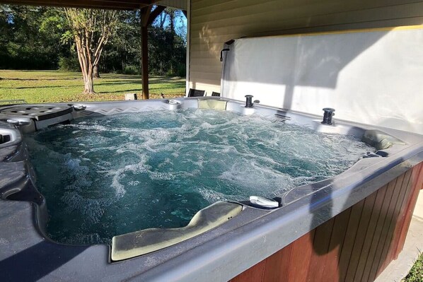 A hot tub with a wooden deck and a view of a grassy yard. - Stewart House with Hot Tub and 3 bedroom (Tickfaw)