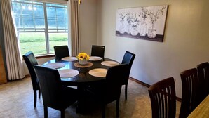 Une salle à manger avec une table ronde, six chaises et un vase rempli de fleurs jaunes.