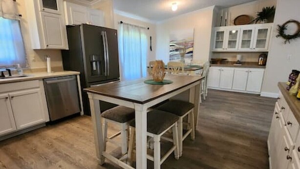 A kitchen with white cabinets, a black refrigerator, a wooden dining table with chairs, and a light fixture on the ceiling. - Thomas House, spacious house in Tickfaw, LA (Tickfaw)