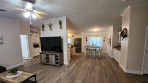 A spacious living room with a flat-screen TV, wooden flooring, and a ceiling fan. - Thomas House, spacious house in Tickfaw, LA (Tickfaw)