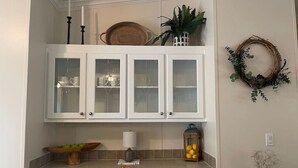 A kitchen with white cabinets, a fruit bowl, a lantern, and a wreath on the wall. - Thomas House, spacious house in Tickfaw, LA (Tickfaw)